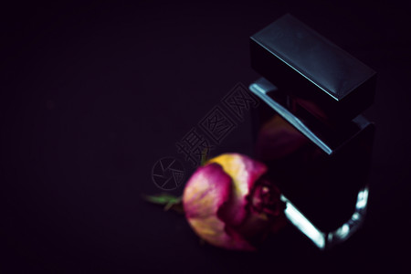 黑色背景上带花的香水瓶图片