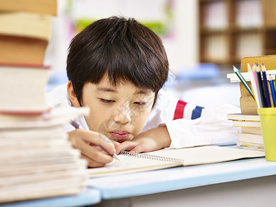 在课堂上做功课的亚洲小学生疲倦和无聊图片