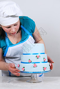 女人装饰三层蓝色蛋糕孤立在白色图片
