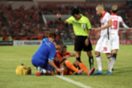 足球比赛中受伤球员的医生和裁判与裁判图片