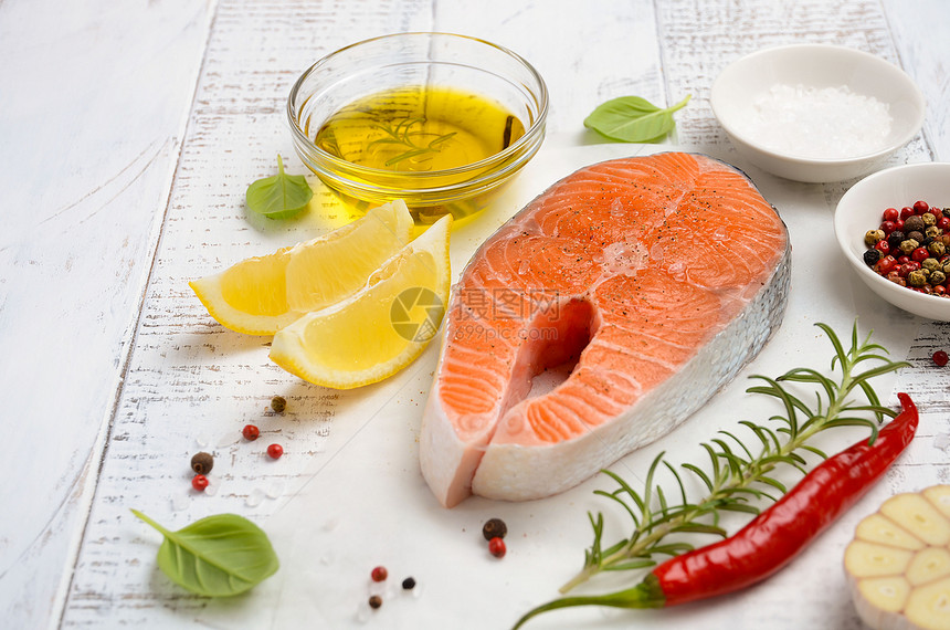 新鲜的生鲑鱼牛排配柠檬橄榄油和质朴的木制背景上的香料制作健康晚餐的配料健康饮食概念选择焦图片