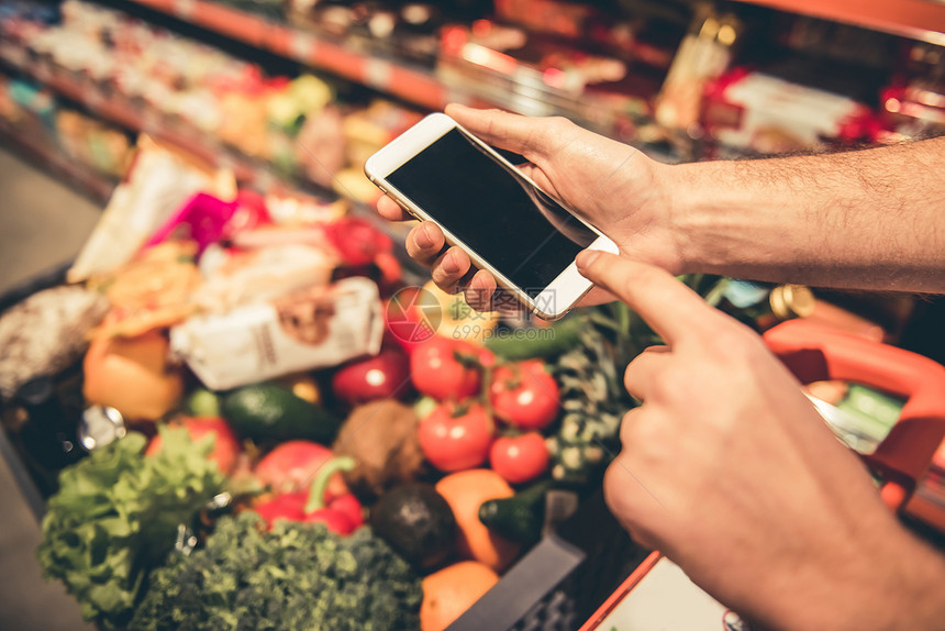 在超市购物时使用手机的人裁剪图像图片