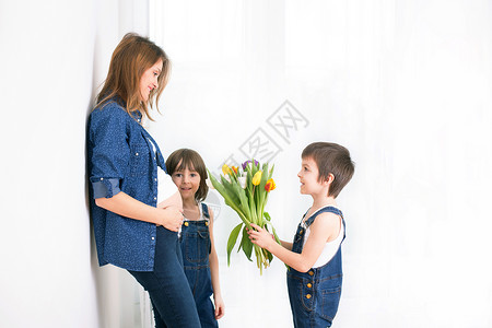 孕妇拥抱孩子接受郁金香花朵用于节日背光图片