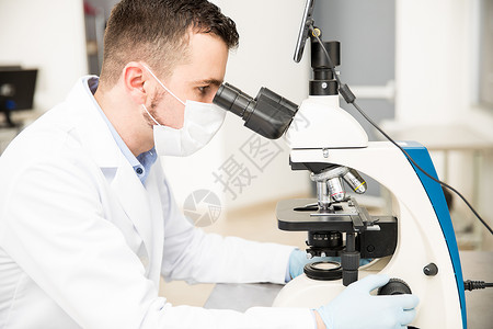 男化学家使用显微镜分析实验室血图片