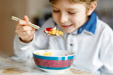 小学生男孩吃麦片加牛奶和浆果图片