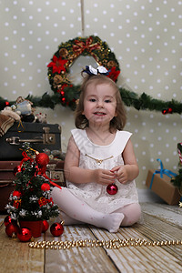 可爱的小女孩穿了圣诞树在房间地背景图片