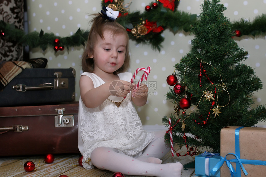 可爱的小女孩穿了圣诞树在房间地图片
