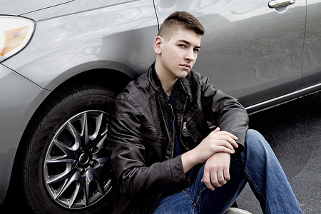 高中男生坐在车轮旁边身着黑色皮夹克的汽图片