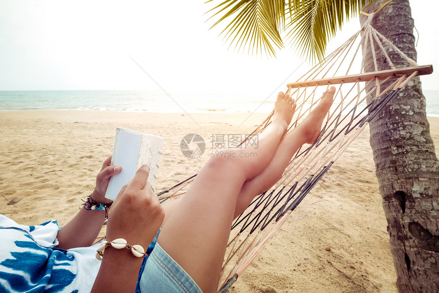 夏天的休闲美丽的感女郎在沙热带海滩的吊床上放松和阅读古图片