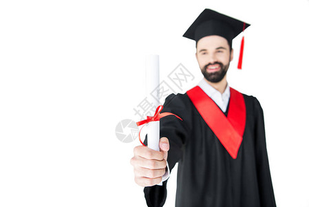 在毕业礼服上微笑的年轻男子持有孤立在白背景图片