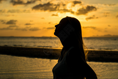 海边日落时年轻女子的剪影图片