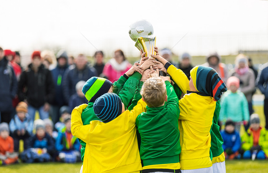 拿着奖杯的年轻足球员庆祝足球橄榄球冠军的男孩儿童锦标赛青年队获胜孩子们图片