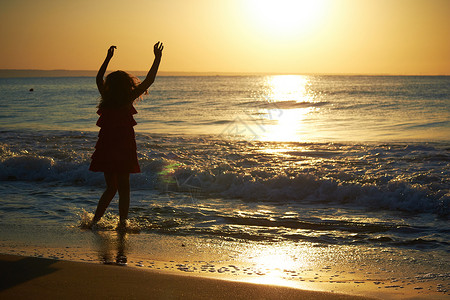 日落时在沙滩上玩耍的女孩背景图片