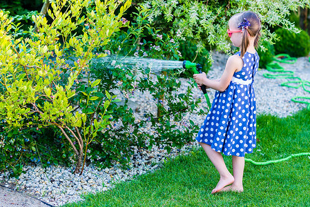 小快乐的小女孩浇水花园图片