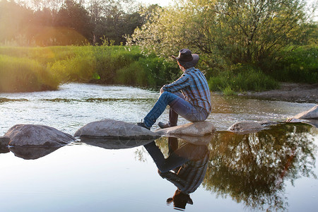 年轻的牛仔在河上欣赏春晚的日落图片