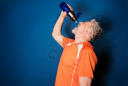 运动成熟男子从运动瓶中饮用图片
