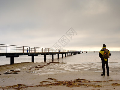 在肮脏的沙滩上独自站立着背包徒步旅行的人图片