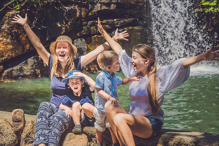 旅游的妇女和儿童举起双手与瀑布对立图片