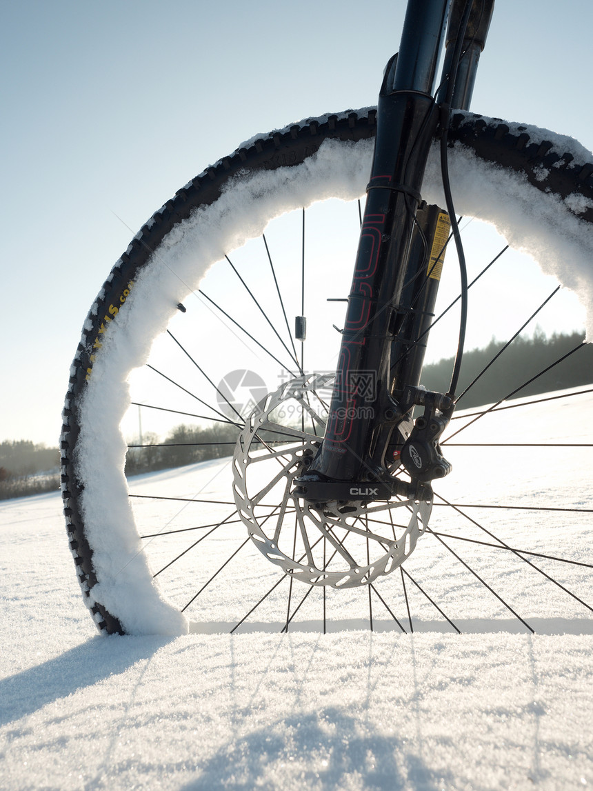 山地自行车前轮在粉雪中刺拳在深雪堆下迷失了道路雪花融化在黑暗的越野轮胎上在该领图片
