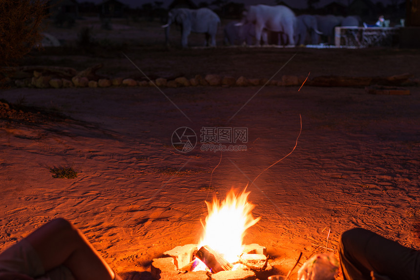 一对夫妇晚上坐在燃烧的营火旁图片