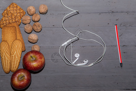 桌上有饼干核桃苹果和耳塞顶视图图片