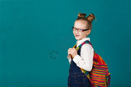 有趣的小女孩背着大背包跳跃图片
