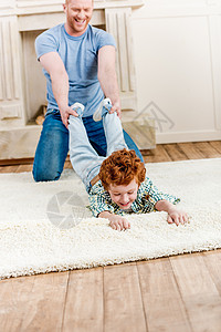 快乐的红发父亲和儿子一起在家地毯上玩乐图片