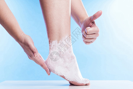 女人用润滑油给干枯的皮肤和精密的脚和高跟鞋霜润湿图片