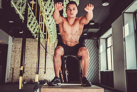 英俊的年轻肌肉运动健壮运动员正在健身房用一个锻炼箱图片