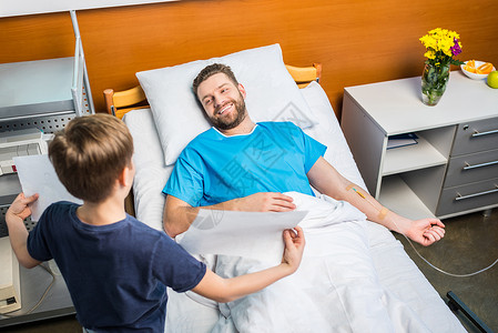 小儿子在病房里给生病的父亲看他的画图片