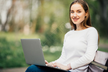 女学生在大学校园的长椅上用笔记图片