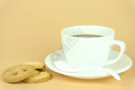 橙色背景上的咖啡杯和咖啡豆图片