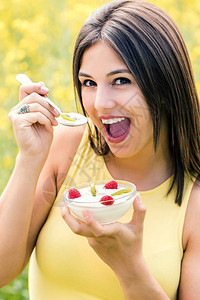 穿着酸奶碗和水果对抗黄花田的年轻女子图片