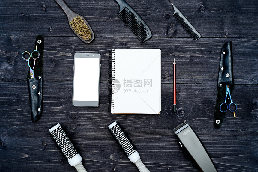 木制背景上的美发师工具与理发工具平躺的空白卡带剪刀梳子和发夹的木桌上的顶视图图片