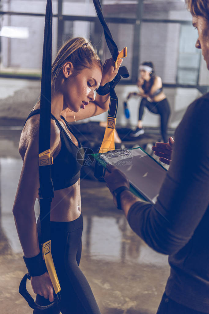 帮助运动妇女使用Trx健身设备锻图片