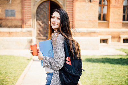 美国大学生在校园里微笑着咖啡和书包图片