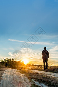 一个人站在路边看着日落风景图片