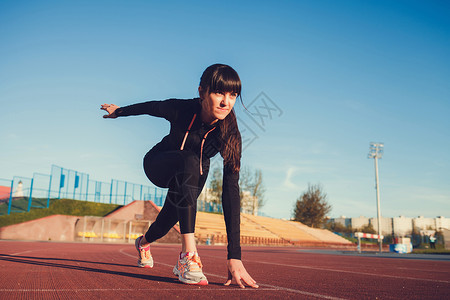 处于起始位置的女运动员准备好跑步即将开始在体育场冲图片