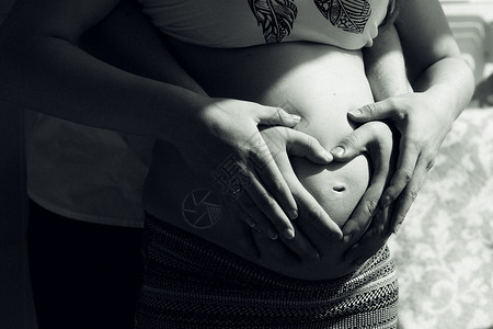 在她怀孕的肚子上画出一对夫妇手的肖像使图片