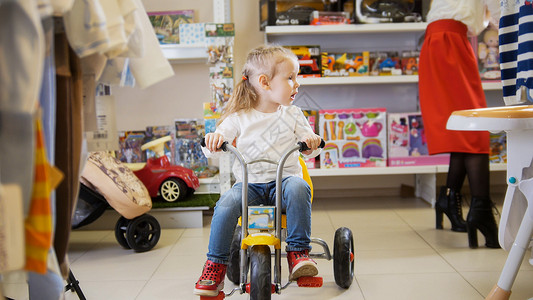 小女孩在儿童商店骑三轮车图片