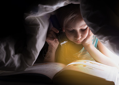 修女在用手电筒的毯子下看一本书漂亮的年轻女孩在儿童室玩得开图片