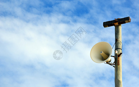 在蓝色天空背景的电线杆上安装户外扩音器警报系统复背景图片