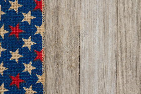 红色白色和蓝色的星在风化的木质背景上用粗麻布丝带图片
