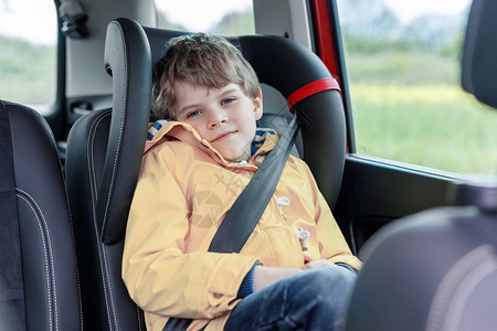 可爱的学龄前儿童男孩穿着黄色雨衣坐在车里图片