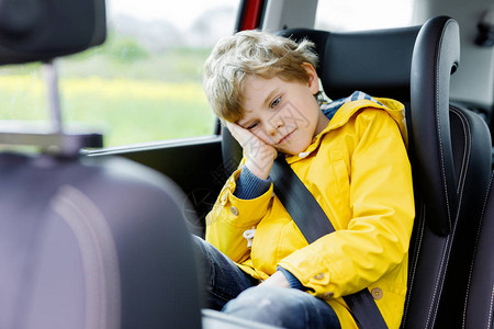 在交通堵塞期间坐在车里的疲倦的学龄前儿童男孩图片