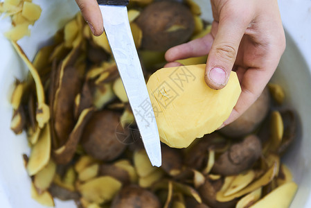 儿童手用厨房刀剥开新鲜黄土豆的详细情况图片