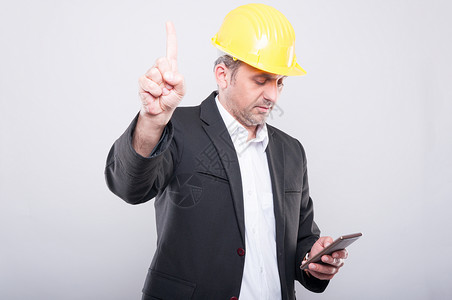 建筑设计师的肖像看着他忙碌的智能手机穿着灰色背图片