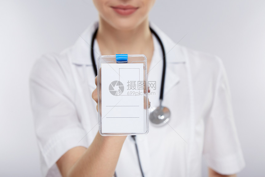 身穿白色医疗制服的女医生在灰色工作室背景中持有个人医疗图片