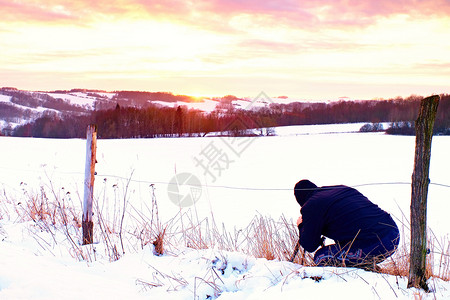 摄影师躺在草原上的雪中拍摄了对面山图片