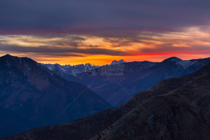 意大利阿尔卑斯山脉高山峰后有多彩的日落雾笼罩了下面的山谷秋天风景图片